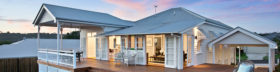 A residential home exterior in a neighborhood at dusk, lit and furnished.